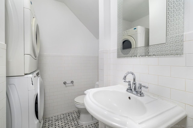 1197 Hope St Apt 7, Stamford, CT 06907 - bathroom with stacked washing machine and dryer, tile walls, lofted ceiling, wainscoting, and tile patterned floors