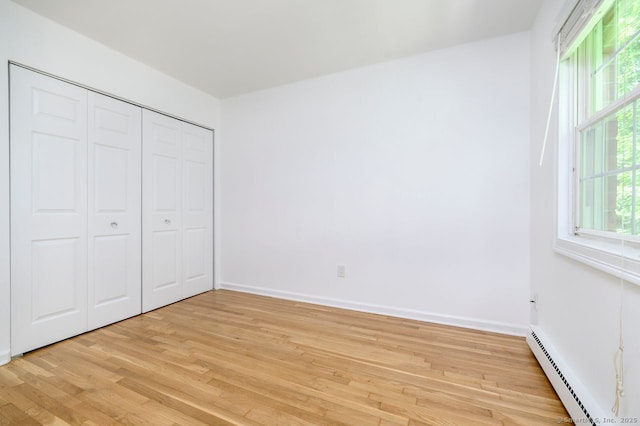 1197 Hope St Apt 7, Stamford, CT 06907 - unfurnished bedroom with a baseboard radiator, light wood-style flooring, multiple windows, and a closet