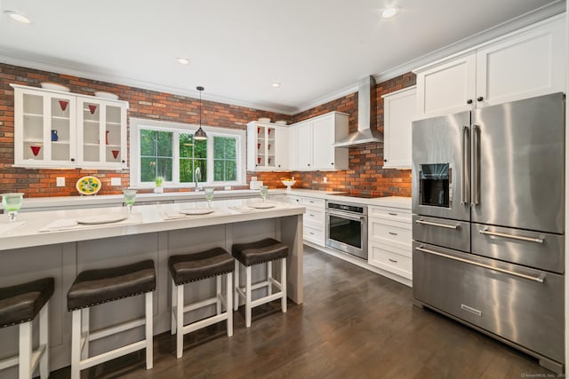 98A Tower Rd, Brookfield, CT 06804 - kitchen with appliances with stainless steel finishes, wall chimney range hood, glass insert cabinets, a breakfast bar area, and white cabinets