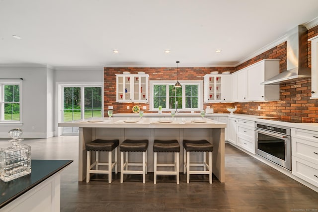 98A Tower Rd, Brookfield, CT 06804 - kitchen with stainless steel oven, wall chimney range hood, crown molding, glass insert cabinets, and a breakfast bar
