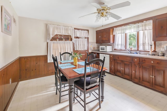 46 W St, Shelton, CT 06484 - dining space featuring wainscoting, a ceiling fan, wood walls, and light floors
