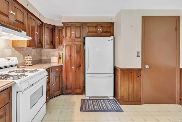 46 W St, Shelton, CT 06484 - kitchen with white appliances, light floors, under cabinet range hood, decorative backsplash, and a wainscoted wall