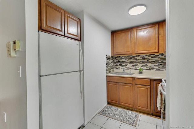 142 Burgundy Hill Ln Unit 142, Middletown, CT 06457 - kitchen featuring freestanding refrigerator, light tile patterned floors, brown cabinetry, light countertops, and tasteful backsplash