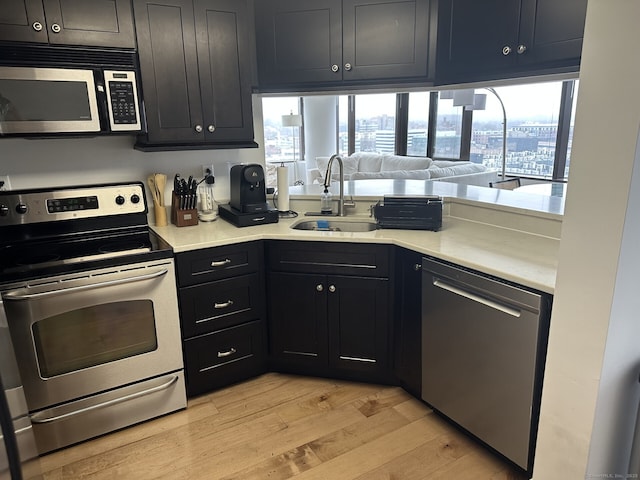 127 Greyrock Pl Apt 1401, Stamford, CT 06901 - kitchen featuring appliances with stainless steel finishes, light wood-type flooring, light countertops, and dark cabinets