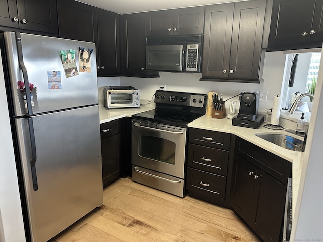 127 Greyrock Pl Apt 1401, Stamford, CT 06901 - kitchen featuring appliances with stainless steel finishes, light wood finished floors, light countertops, and dark cabinetry