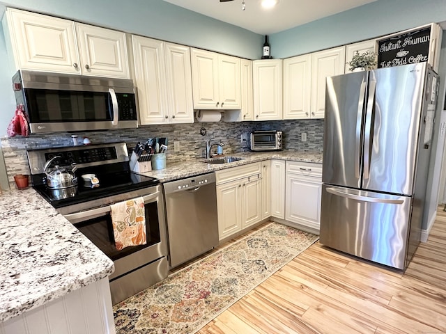 85 Viscount Dr Unit 4E, Milford, CT 06460 - kitchen with stainless steel appliances, decorative backsplash, light wood finished floors, and light stone counters