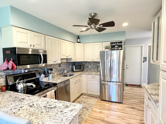 85 Viscount Dr Unit 4E, Milford, CT 06460 - kitchen featuring stainless steel appliances, backsplash, a ceiling fan, light wood-style flooring, and light stone counters