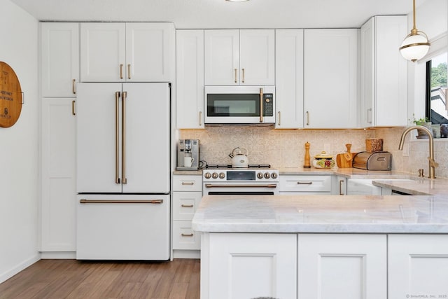 583 Heritage Vlg Unit A, Southbury, CT 06488 - kitchen featuring premium appliances, white cabinets, light stone countertops, tasteful backsplash, and wood finished floors