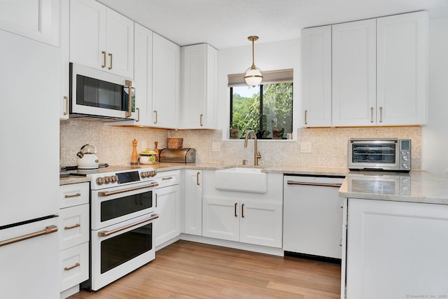 583 Heritage Vlg Unit A, Southbury, CT 06488 - kitchen with white appliances, white cabinets, light wood finished floors, decorative backsplash, and decorative light fixtures