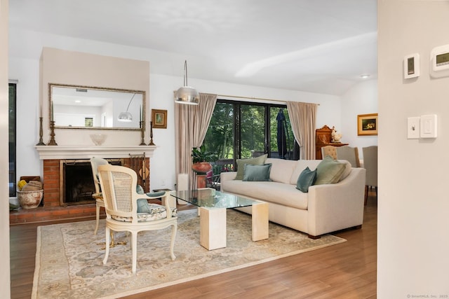583 Heritage Vlg Unit A, Southbury, CT 06488 - living room featuring wood finished floors, a brick fireplace, and vaulted ceiling