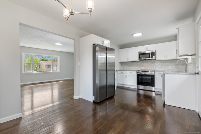 231 Lincolndale Dr, Waterbury, CT 06704 - kitchen with appliances with stainless steel finishes, decorative backsplash, white cabinets, dark wood finished floors, and light stone counters