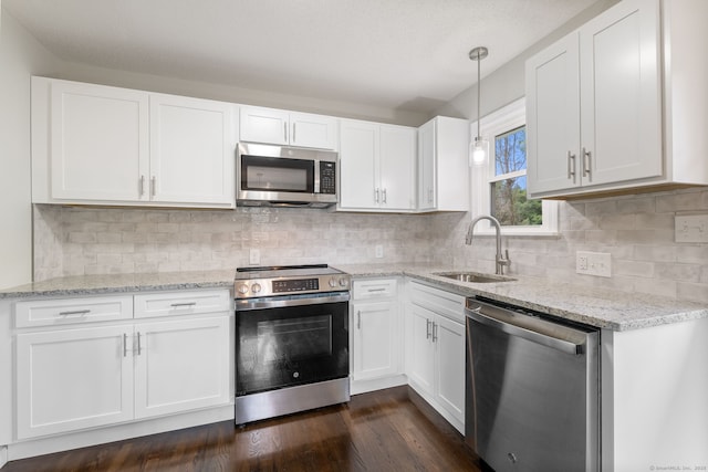 231 Lincolndale Dr, Waterbury, CT 06704 - kitchen featuring appliances with stainless steel finishes, white cabinets, light stone countertops, dark wood finished floors, and decorative light fixtures
