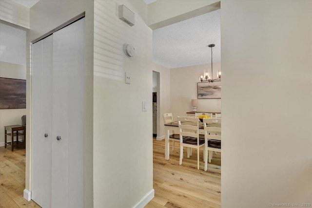 177 New Britain Ave Unit 177, Farmington, CT 06085 - hallway with light wood-type flooring, a chandelier, and a textured ceiling