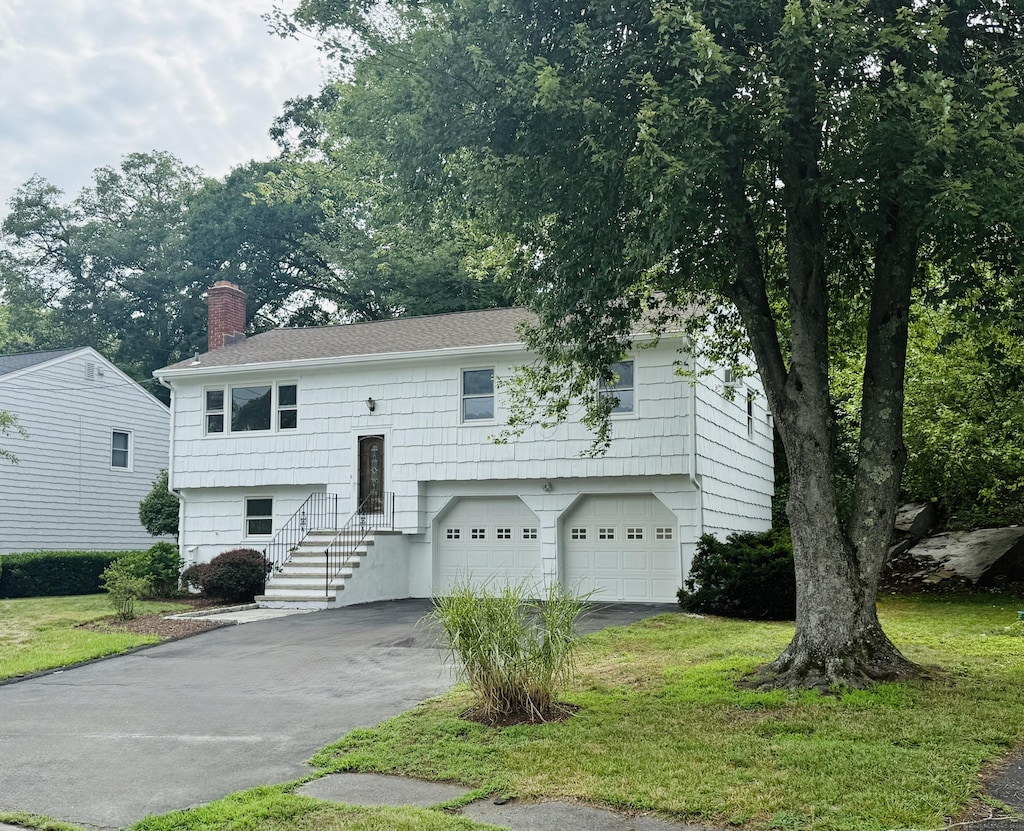 53 Valley View Rd, Norwalk, CT 06851 - split foyer home with driveway, a chimney, a garage, and a front lawn