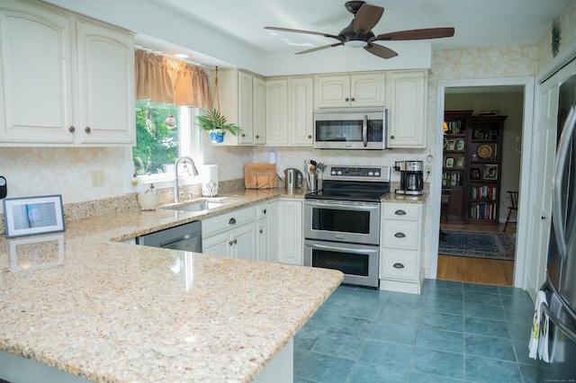 95 Holly Mar Hill Rd, North Branford, CT 06472 - kitchen with stainless steel appliances, a peninsula, a ceiling fan, light stone counters, and tile patterned floors