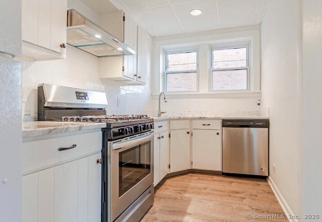 77 Glenbrook Rd Apt 203, Stamford, CT 06902 - kitchen featuring appliances with stainless steel finishes, range hood, light wood-type flooring, tasteful backsplash, and light stone countertops