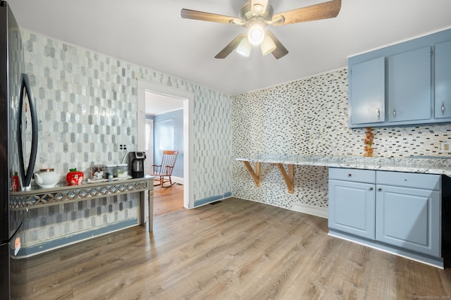 28 W High St, New London, CT 06320 - kitchen featuring wallpapered walls, blue cabinets, freestanding refrigerator, ceiling fan, and light wood finished floors