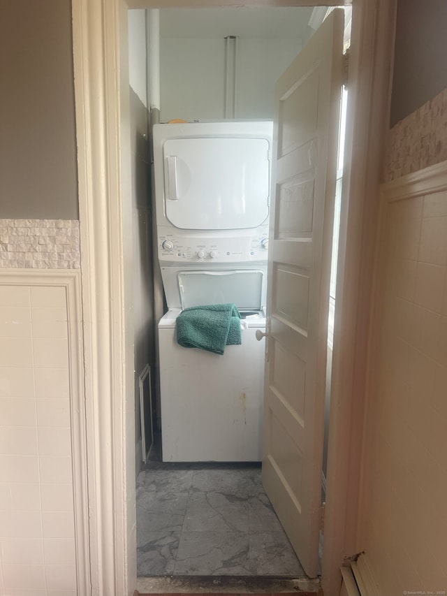 155 Summerfield Ave, Bridgeport, CT 06610 - laundry room featuring stacked washer / drying machine, tile walls, and wainscoting