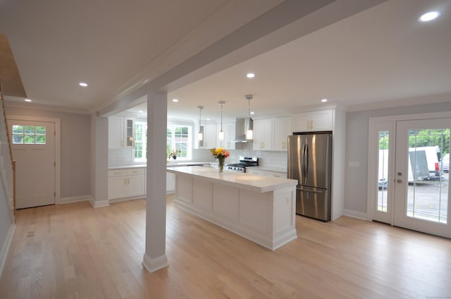 401 Unity Rd, Trumbull, CT 06611 - kitchen featuring stainless steel appliances, wall chimney range hood, light countertops, white cabinetry, and decorative backsplash