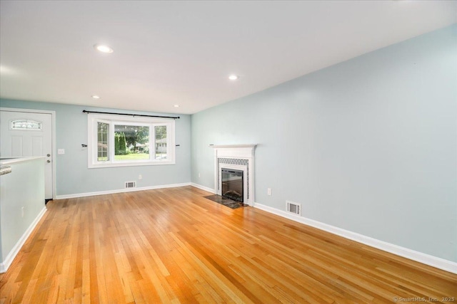 234 Forest Dr, Wethersfield, CT 06109 - unfurnished living room featuring light wood-type flooring, a tiled fireplace, and recessed lighting