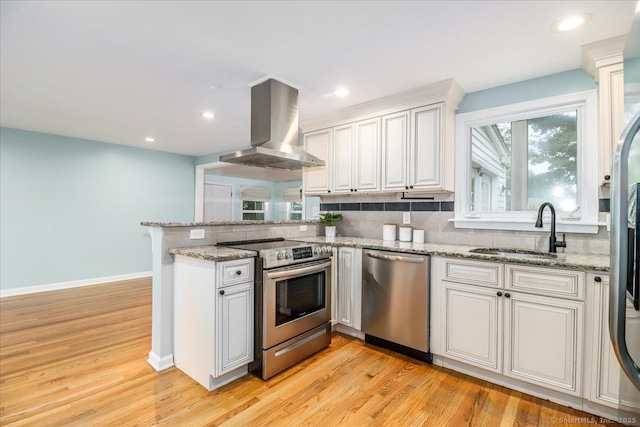 234 Forest Dr, Wethersfield, CT 06109 - kitchen with appliances with stainless steel finishes, wall chimney range hood, backsplash, a peninsula, and recessed lighting