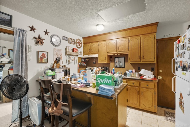 190 Main St, Plainfield, CT 06354 - kitchen featuring freestanding refrigerator, a textured ceiling, a breakfast bar, a peninsula, and light tile patterned flooring