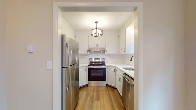 10 Cianci Ave Apt 9, Plainville, CT 06062 - kitchen featuring stainless steel appliances, under cabinet range hood, light wood-style flooring, tasteful backsplash, and white cabinetry