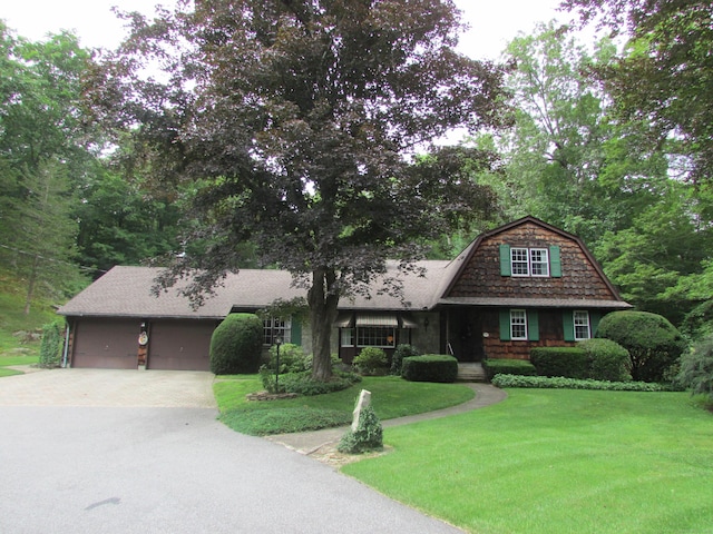 view of front of property featuring driveway, an attached garage, a gambrel roof, a front yard, and roof with shingles