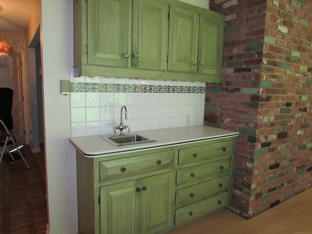 kitchen with light countertops, decorative backsplash, wood finished floors, and green cabinetry