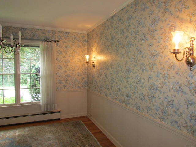 empty room featuring a chandelier, wood finished floors, a baseboard heating unit, wainscoting, and crown molding