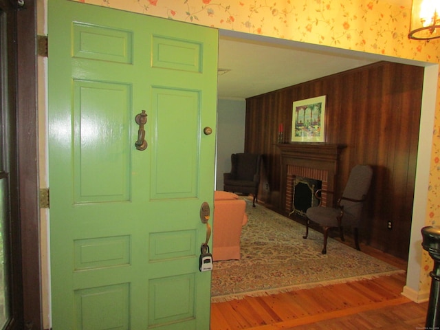 entryway featuring wallpapered walls, wood finished floors, and a brick fireplace