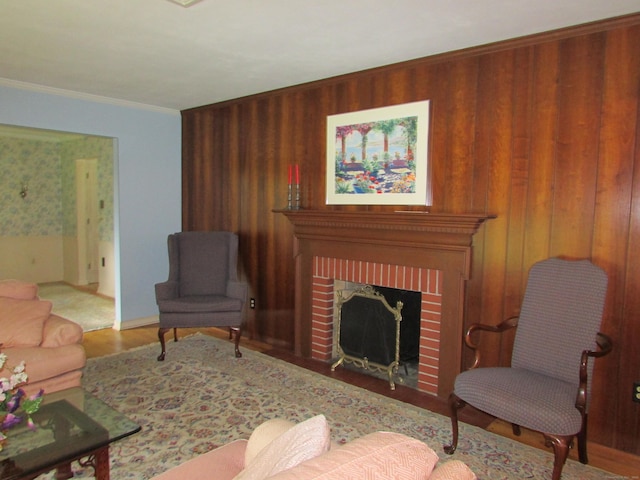 living room with wood walls, wood finished floors, ornamental molding, and a brick fireplace