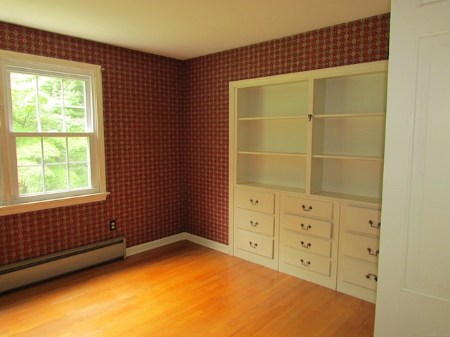 unfurnished bedroom featuring a baseboard radiator, light wood-type flooring, and wallpapered walls