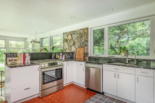 96 Sherman Rd, New Milford, CT 06776 - kitchen featuring appliances with stainless steel finishes, dark stone counters, a peninsula, white cabinetry, and a textured ceiling