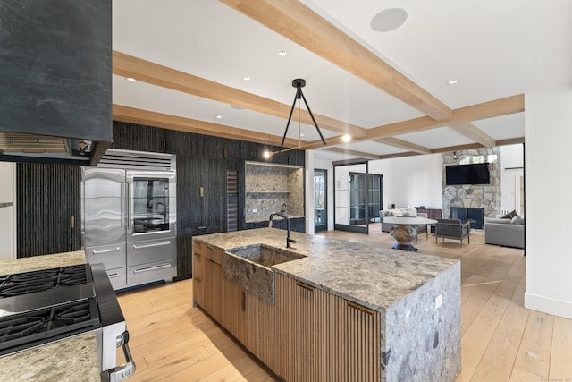22 Serene Way, Newtown, CT 06470 - kitchen with beamed ceiling, light wood-type flooring, a kitchen island with sink, light stone countertops, and a stone fireplace