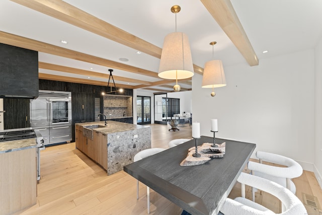 22 Serene Way, Newtown, CT 06470 - kitchen featuring beam ceiling, light wood-type flooring, gas stove, a kitchen island with sink, and light stone countertops
