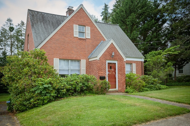 65 Willard St, Hamden, CT 06518 - view of front of property with a shingled roof, brick siding, a front lawn, and a chimney