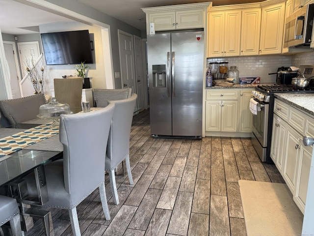 15 Edwards St, Bridgeport, CT 06606 - kitchen featuring appliances with stainless steel finishes, light wood-style flooring, backsplash, light stone counters, and cream cabinetry