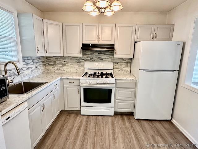 2390 State St Apt 7J, Hamden, CT 06517 - kitchen with white appliances, under cabinet range hood, light wood-style flooring, a chandelier, and white cabinets