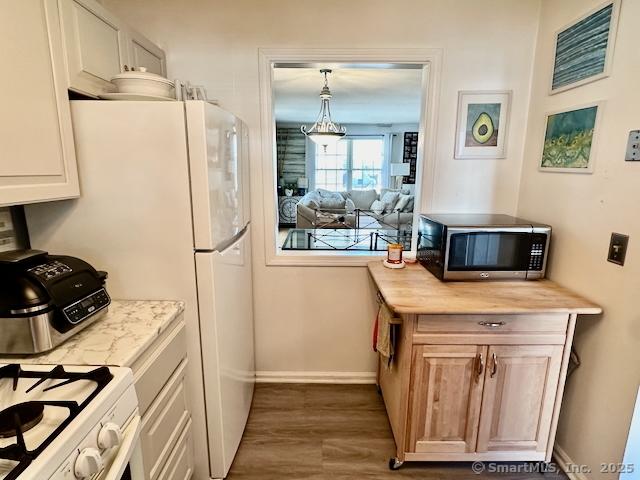 2390 State St Apt 7J, Hamden, CT 06517 - kitchen featuring stainless steel microwave, light countertops, dark wood-type flooring, and freestanding refrigerator