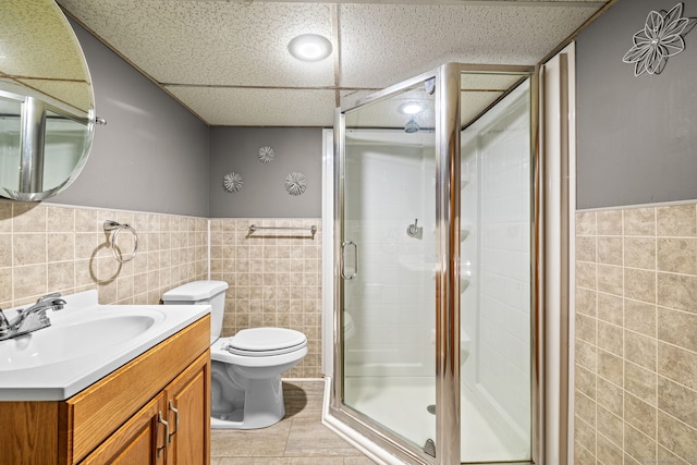 128 Auburn St, Stratford, CT 06614 - bathroom featuring tile walls, vanity, a shower stall, a wainscoted wall, and a paneled ceiling