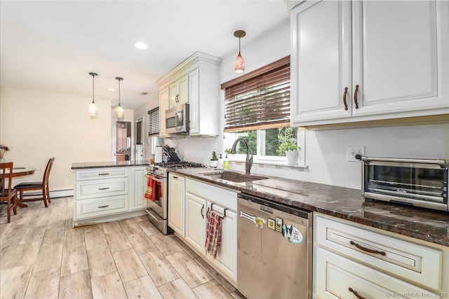 129 Russell Ave, Orange, CT 06477 - kitchen featuring appliances with stainless steel finishes, a peninsula, decorative light fixtures, light wood-type flooring, and dark stone counters