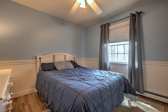 662 Booth Hill Rd, Trumbull, CT 06611 - bedroom with wainscoting, a baseboard heating unit, wood finished floors, and ceiling fan