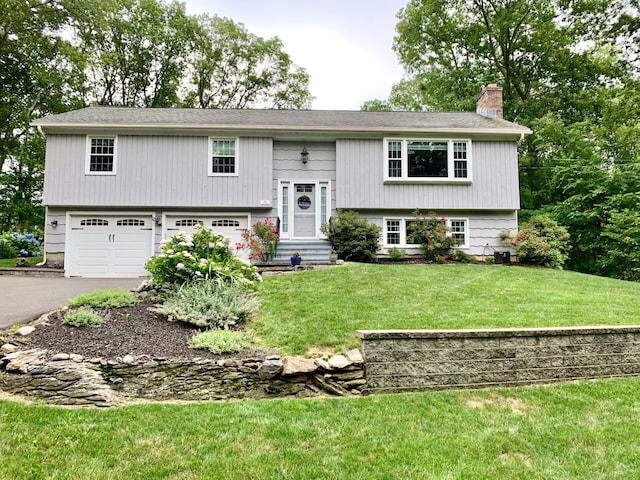 662 Booth Hill Rd, Trumbull, CT 06611 - raised ranch featuring a chimney, a garage, asphalt driveway, a front yard, and entry steps