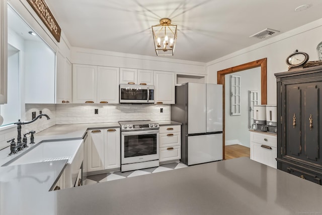 16 Pond Crest Rd, Danbury, CT 06811 - kitchen with appliances with stainless steel finishes, backsplash, white cabinets, and a chandelier