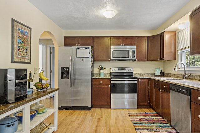 420 Newcomb Rd, North Kingston, Rhode Island, RI 02852 - kitchen featuring stainless steel appliances, light stone countertops, arched walkways, and light wood-style floors