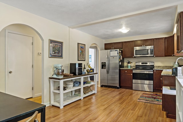 420 Newcomb Rd, North Kingston, Rhode Island, RI 02852 - kitchen featuring stainless steel appliances, arched walkways, light wood finished floors, and dark brown cabinets