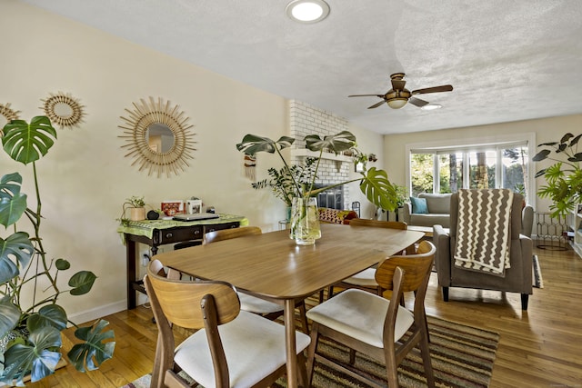 420 Newcomb Rd, North Kingston, Rhode Island, RI 02852 - dining area with ceiling fan, wood finished floors, a textured ceiling, and a fireplace