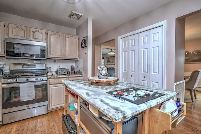 68 Benjamin Rd, East Haven, CT 06513 - kitchen with stainless steel appliances, light wood-style floors, light stone countertops, and a center island