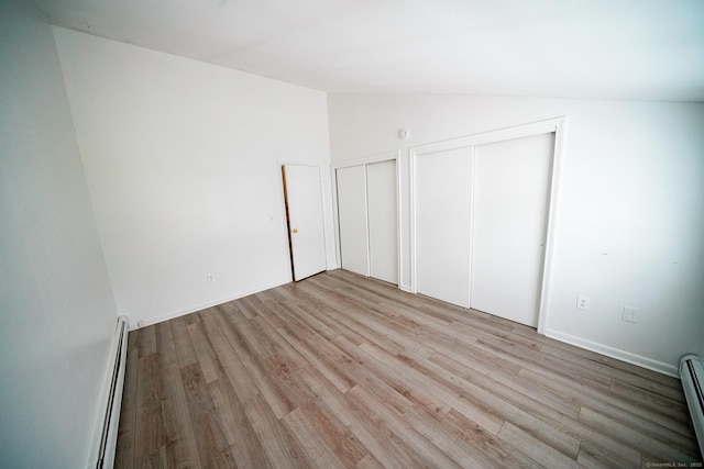 50 E Hill Rd Apt 2H, Canton, CT 06019 - unfurnished bedroom featuring multiple closets, light wood-style floors, lofted ceiling, and a baseboard radiator